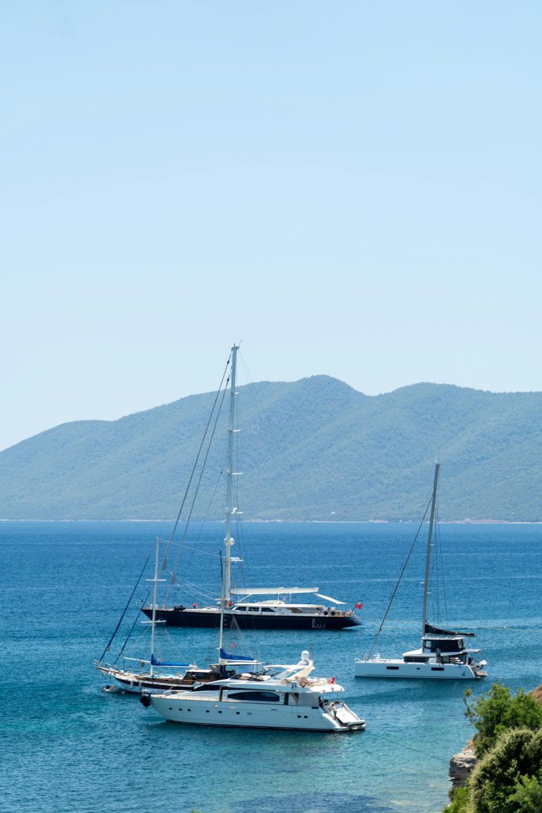 Elegant yachts resting in a serene bay with mountains in the background, perfect for luxurious getaways.